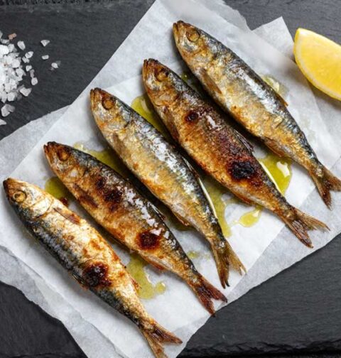 Gebakken sardines op vetvrij papier met zeezout en citroen