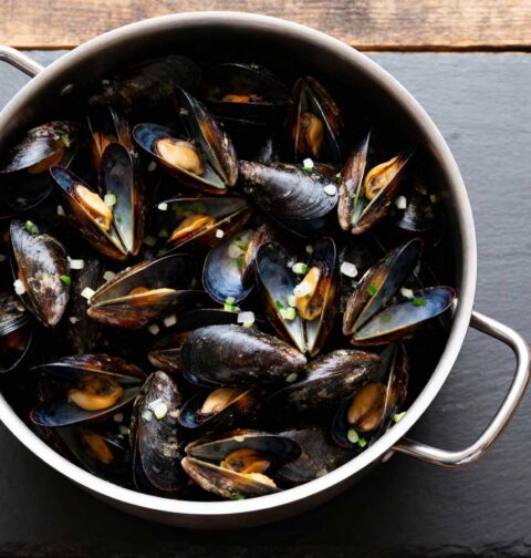 Mosselen koken in een grote pan met smaakmakers