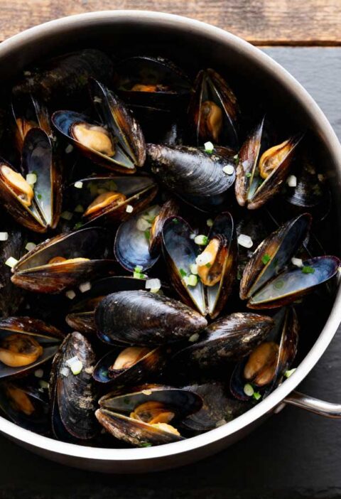 Mosselen koken in een grote pan met smaakmakers