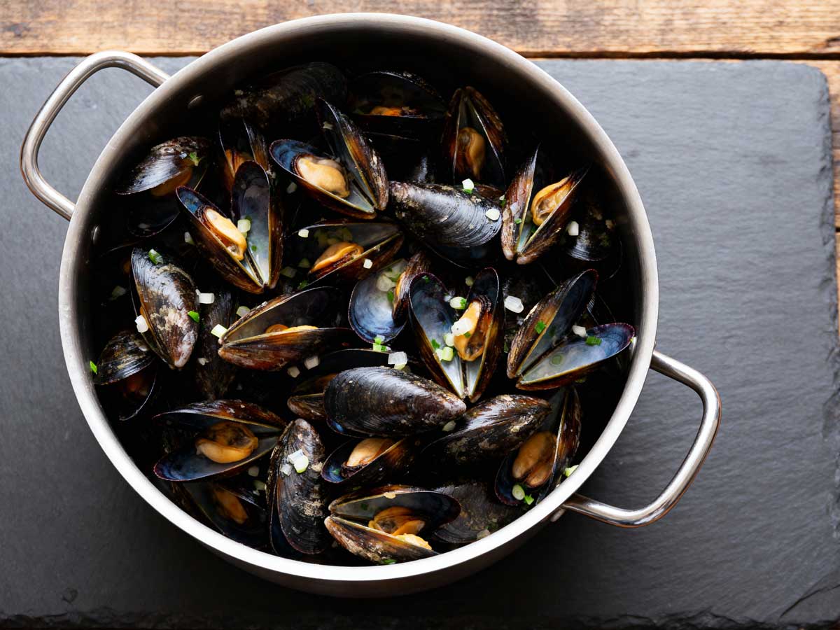 Mosselen koken in een grote pan met smaakmakers