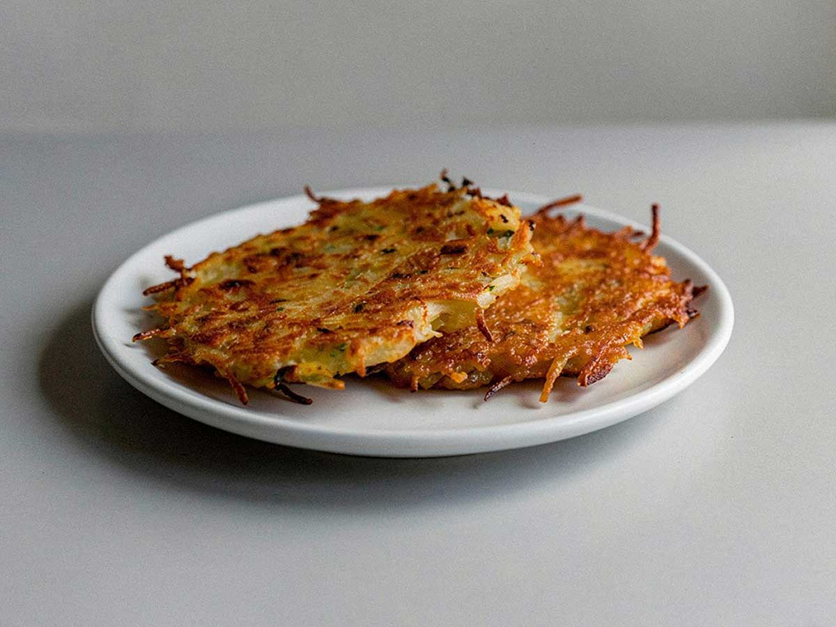 2 net gebakken aardappelpannenkoeken op een wit bordje.