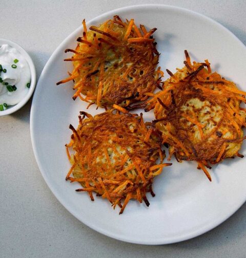 3 aardappel-wortel pannenkoekjes op een bord, met daarnaast de kruidendip.