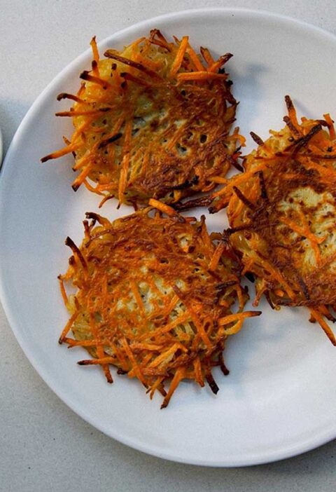 3 aardappel-wortel pannenkoekjes op een bord, met daarnaast de kruidendip.