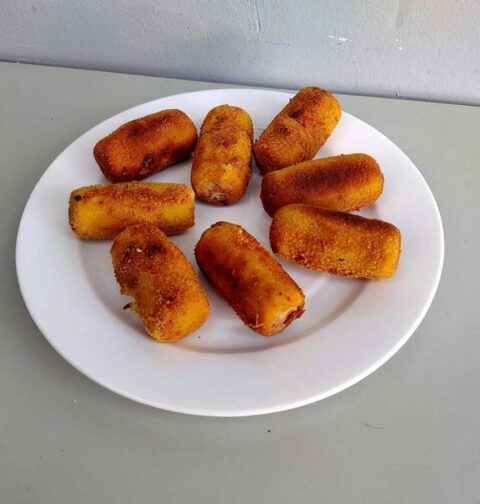 Een bordje met net gefrituurde aardappelkroketjes.