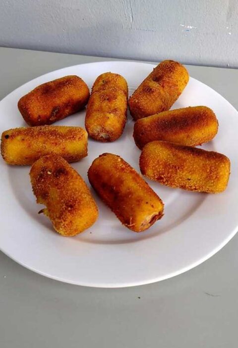 Een bordje met net gefrituurde aardappelkroketjes.