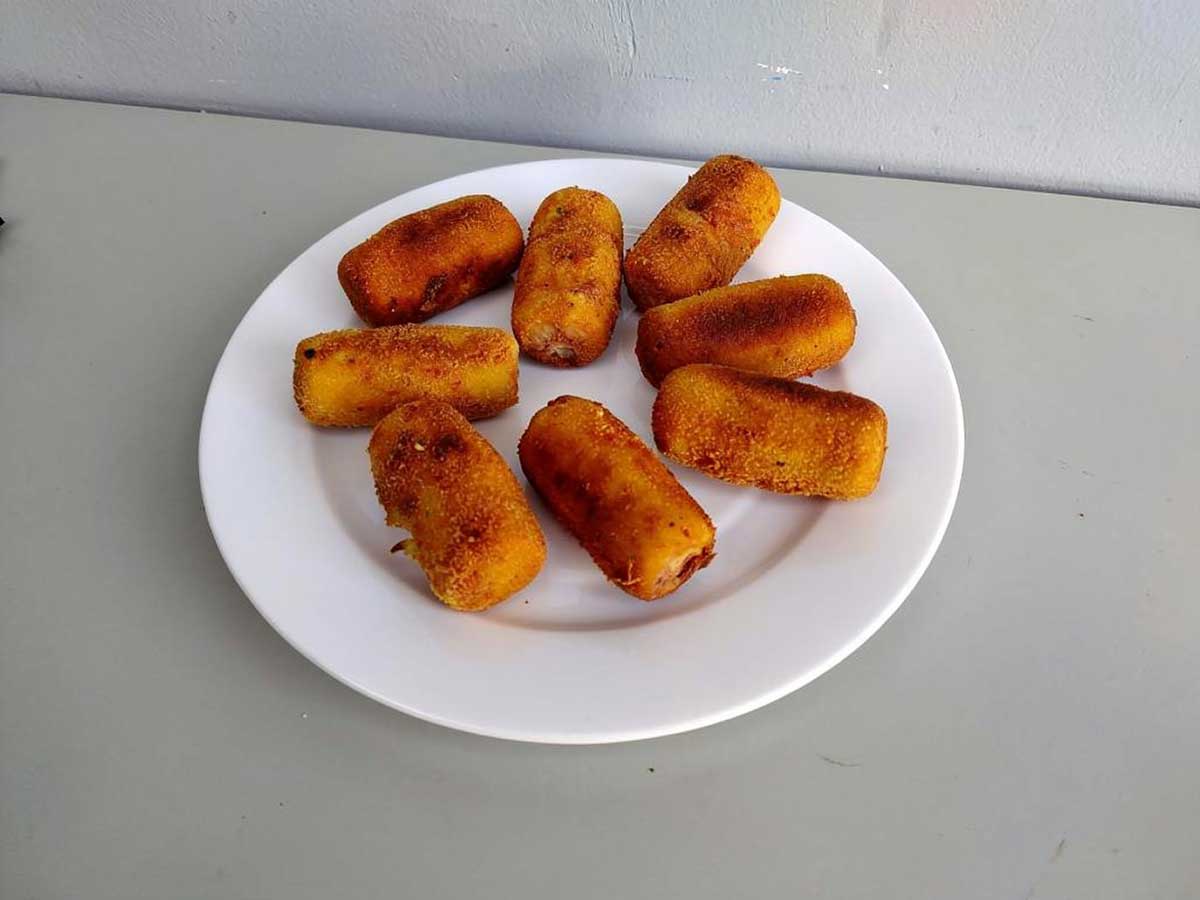 Een bordje met net gefrituurde aardappelkroketjes.