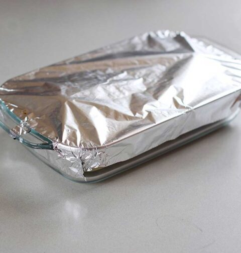 Een ovenschotel half ingepakt met aluminiumfolie.