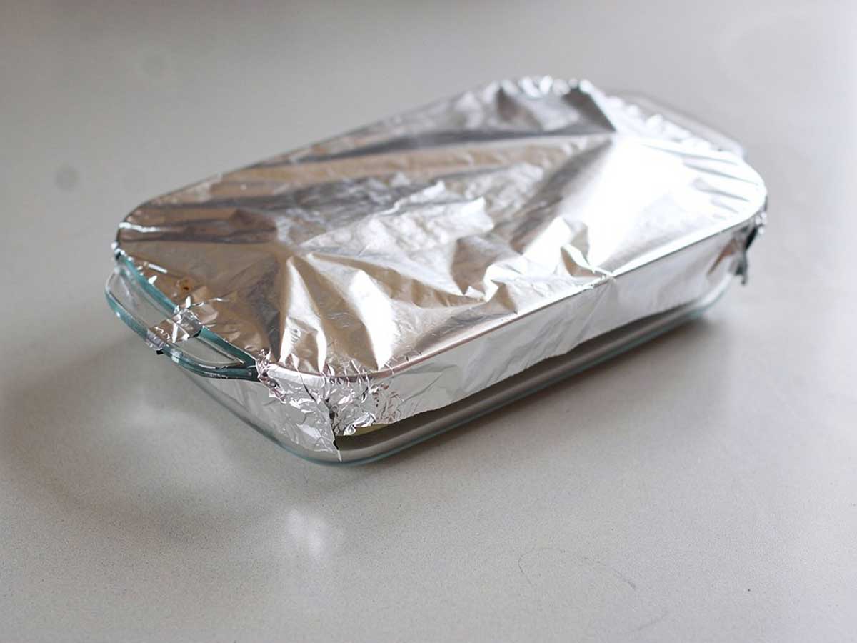 Een ovenschotel half ingepakt met aluminiumfolie.