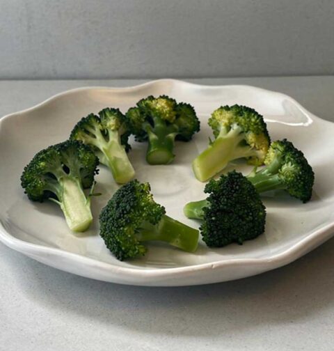 Opgewarmde broccoli op een wit bordje.