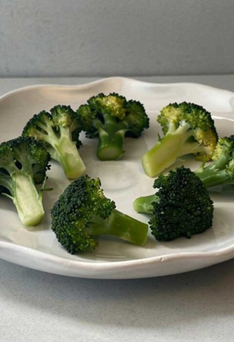 Opgewarmde broccoli op een wit bordje.