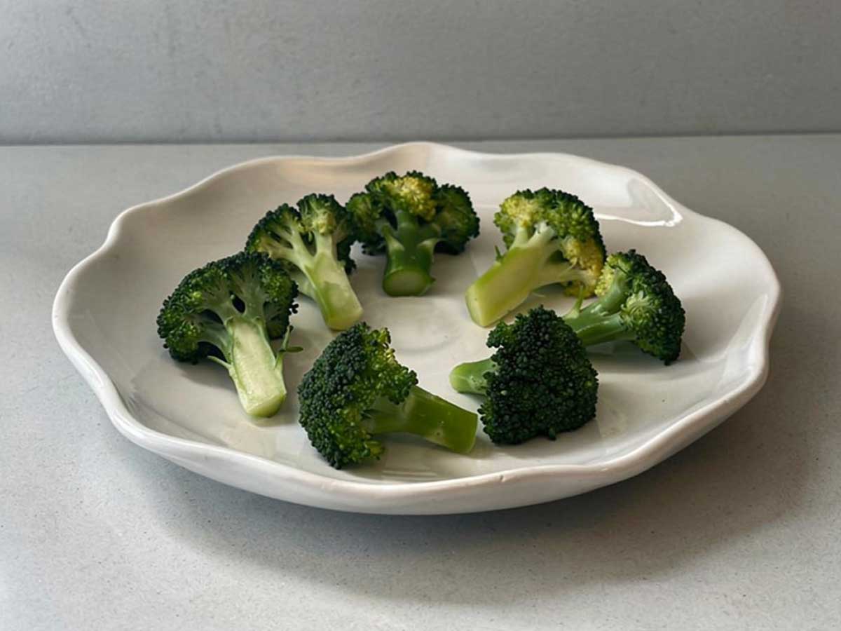 Opgewarmde broccoli op een wit bordje.