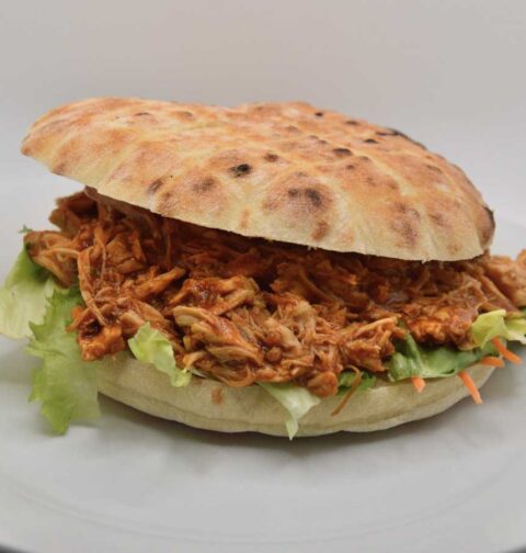 Een broodje pulled pork op een wit bord.
