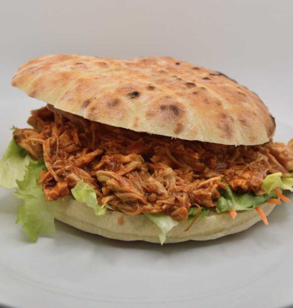 Een broodje pulled pork op een wit bord.