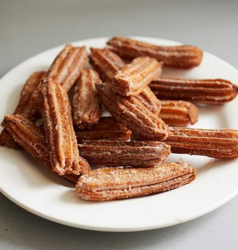 13 churros op en wit bordje, nog zonder suiker.