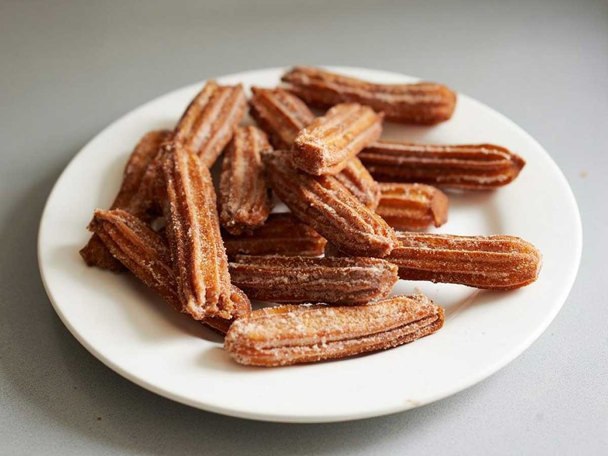 13 churros op en wit bordje, nog zonder suiker.