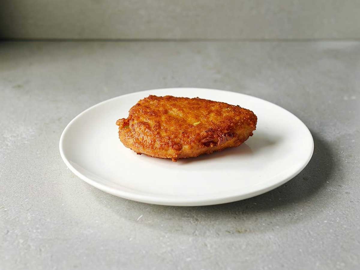 Een gebakken cordon bleu op een wit bord.