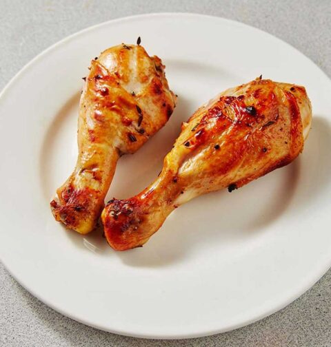 2 heerlijk gebakken drumsticks op een wit bord.