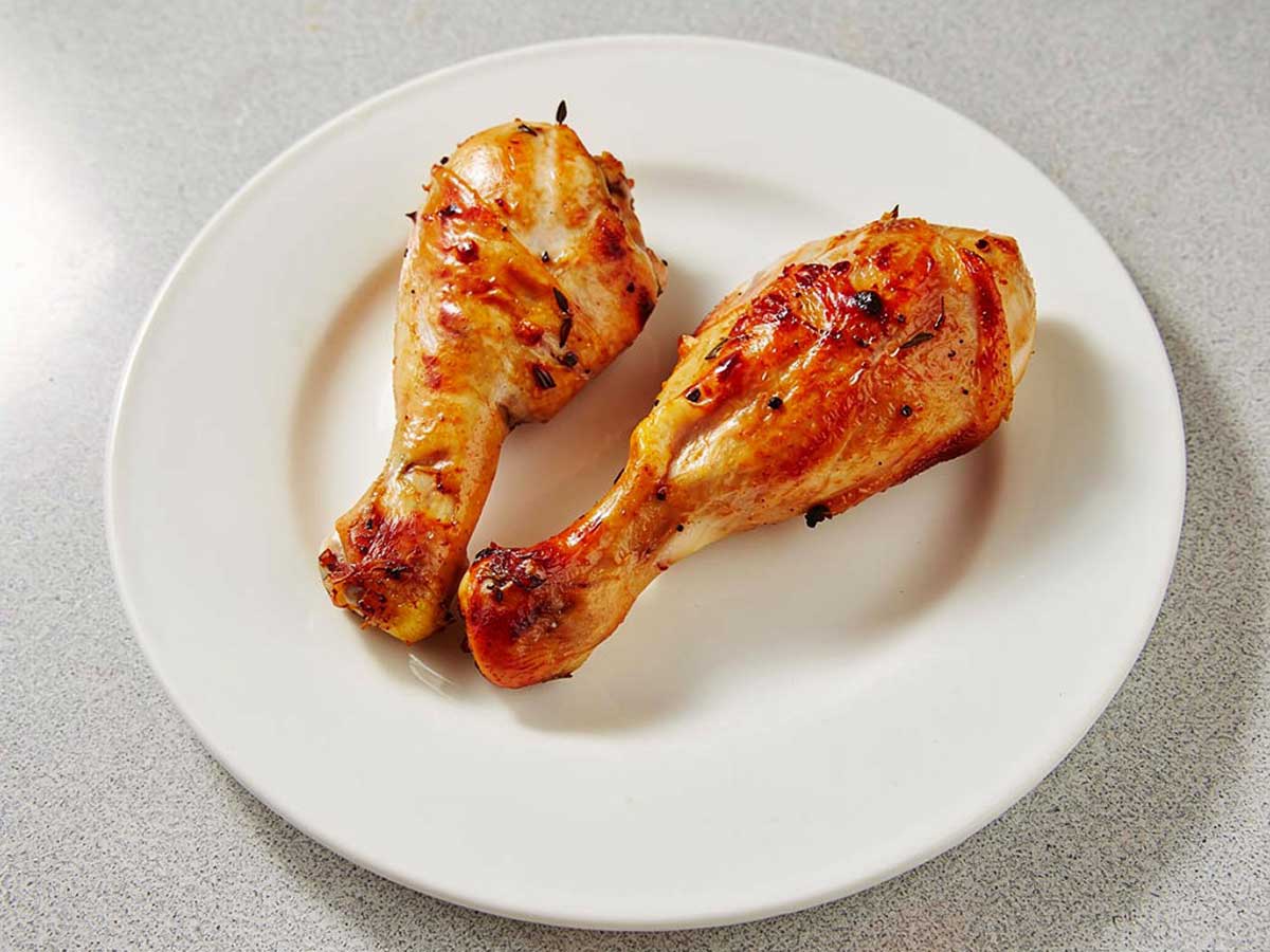 2 heerlijk gebakken drumsticks op een wit bord.
