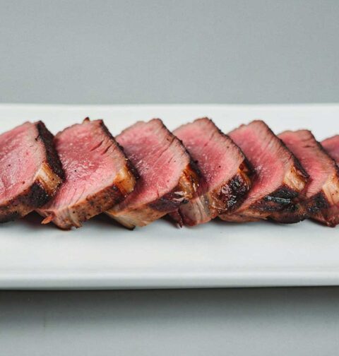 Een in plakjes gesneden entrecote, op een witte schaal.
