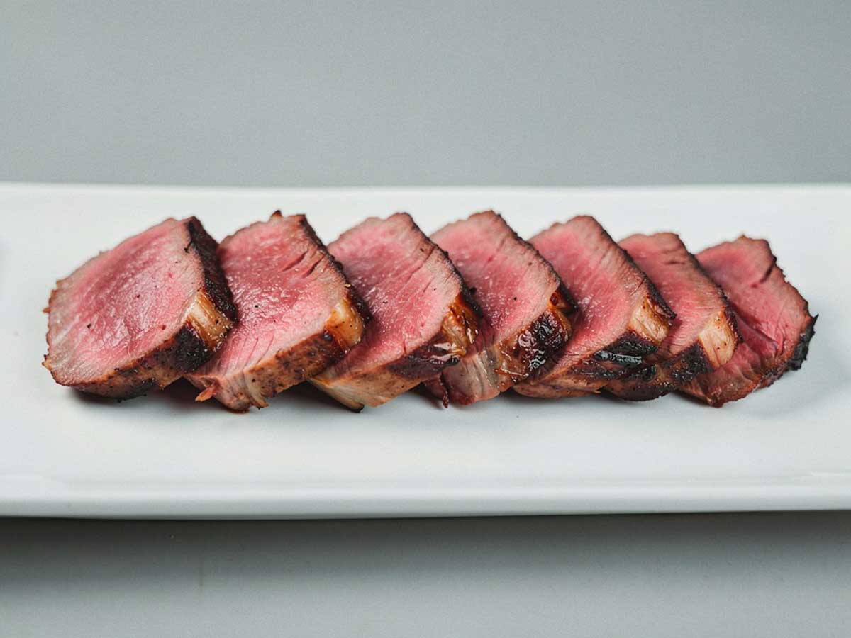 Een in plakjes gesneden entrecote, op een witte schaal.