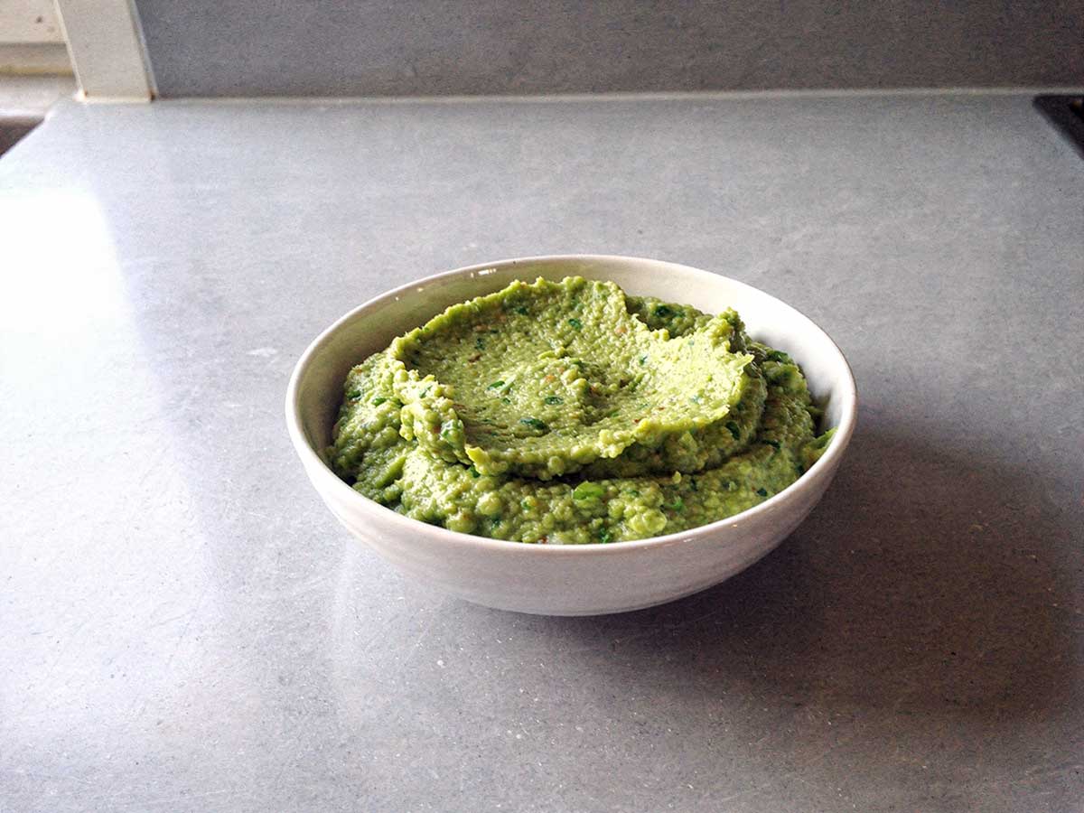 Een schaaltje met grof gepureerde erwtenpuree.