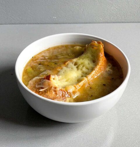 Een soepkom met Franse uiensoep en een gegratineerd stukje stobrood.