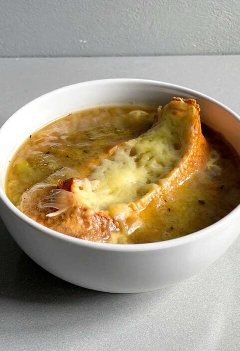 Een soepkom met Franse uiensoep en een gegratineerd stukje stobrood.