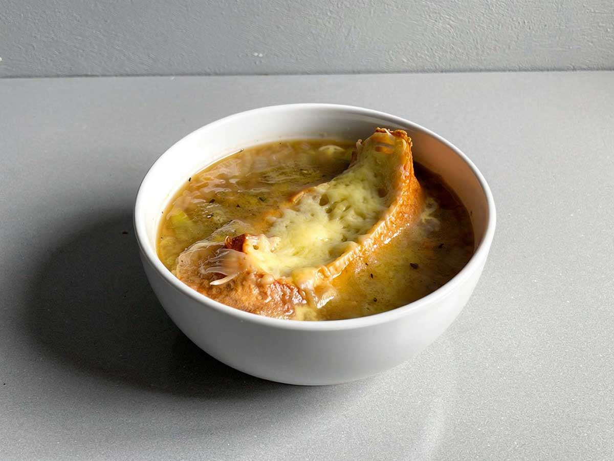 Een soepkom met Franse uiensoep en een gegratineerd stukje stobrood.