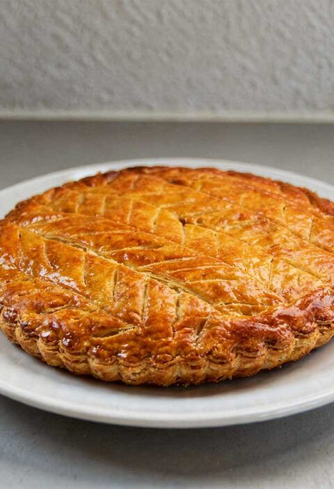 Een hele galette des rois op een wit rond bord.