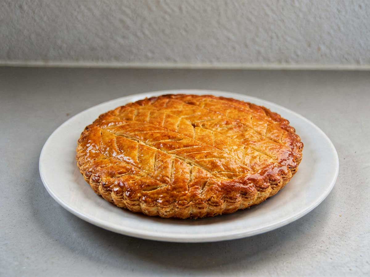 Een hele galette des rois op een wit rond bord.
