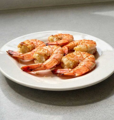 5 gebakken gamba's op een wit bord.
