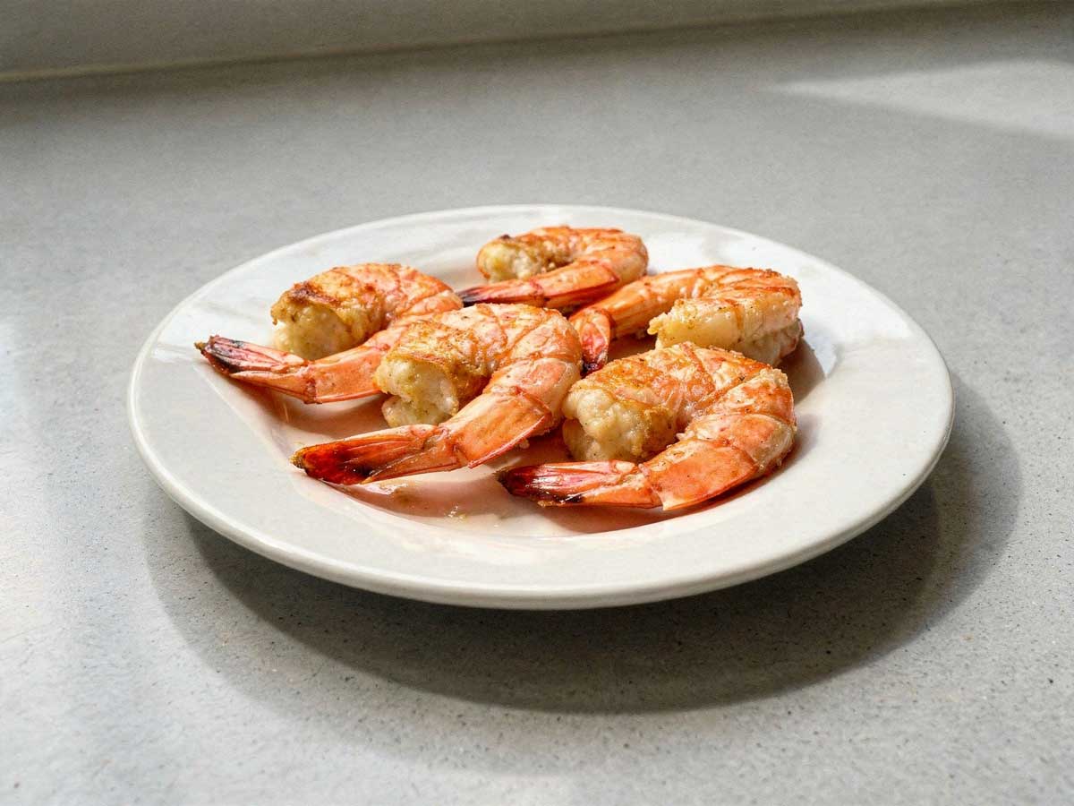 5 gebakken gamba's op een wit bord.