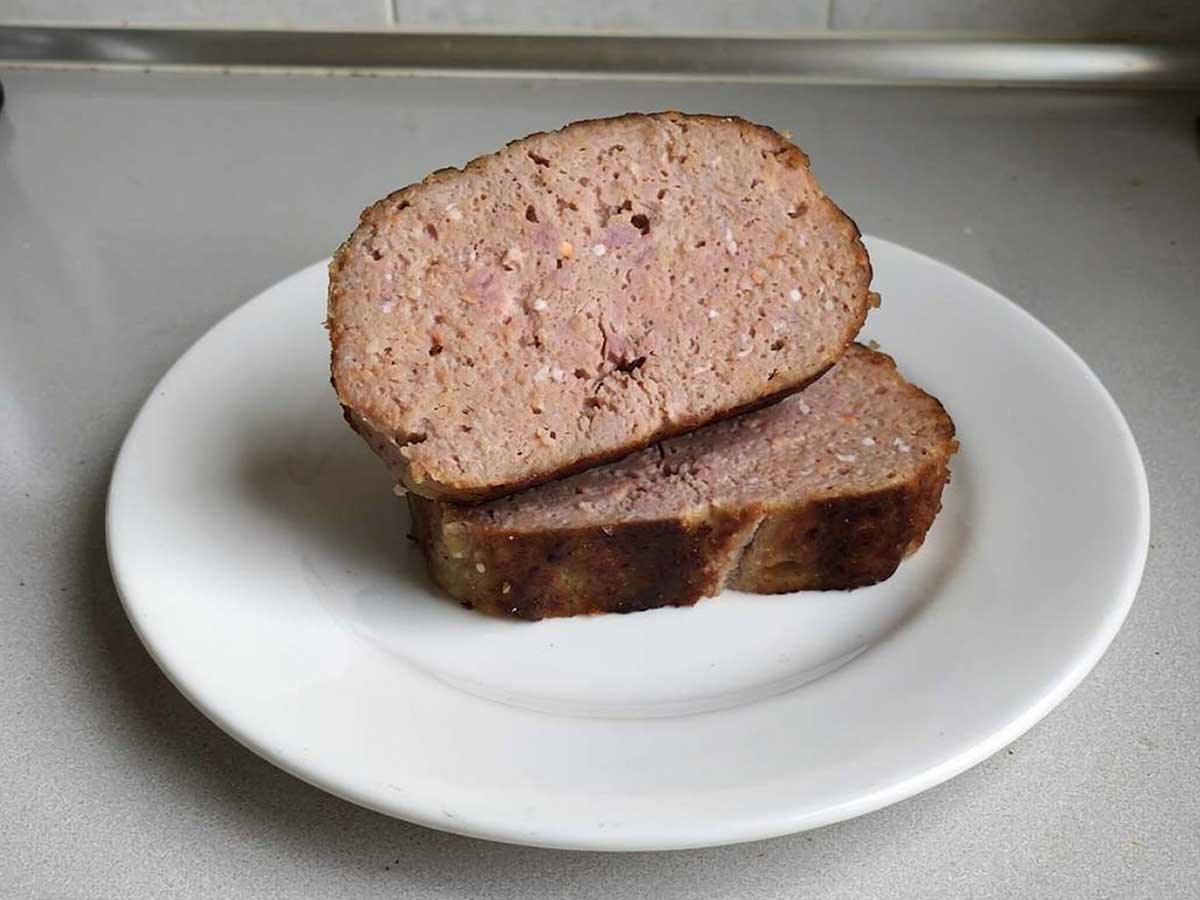 2 plakken zelfgemaakt en gebakken gehaktbrood op een wit bord.