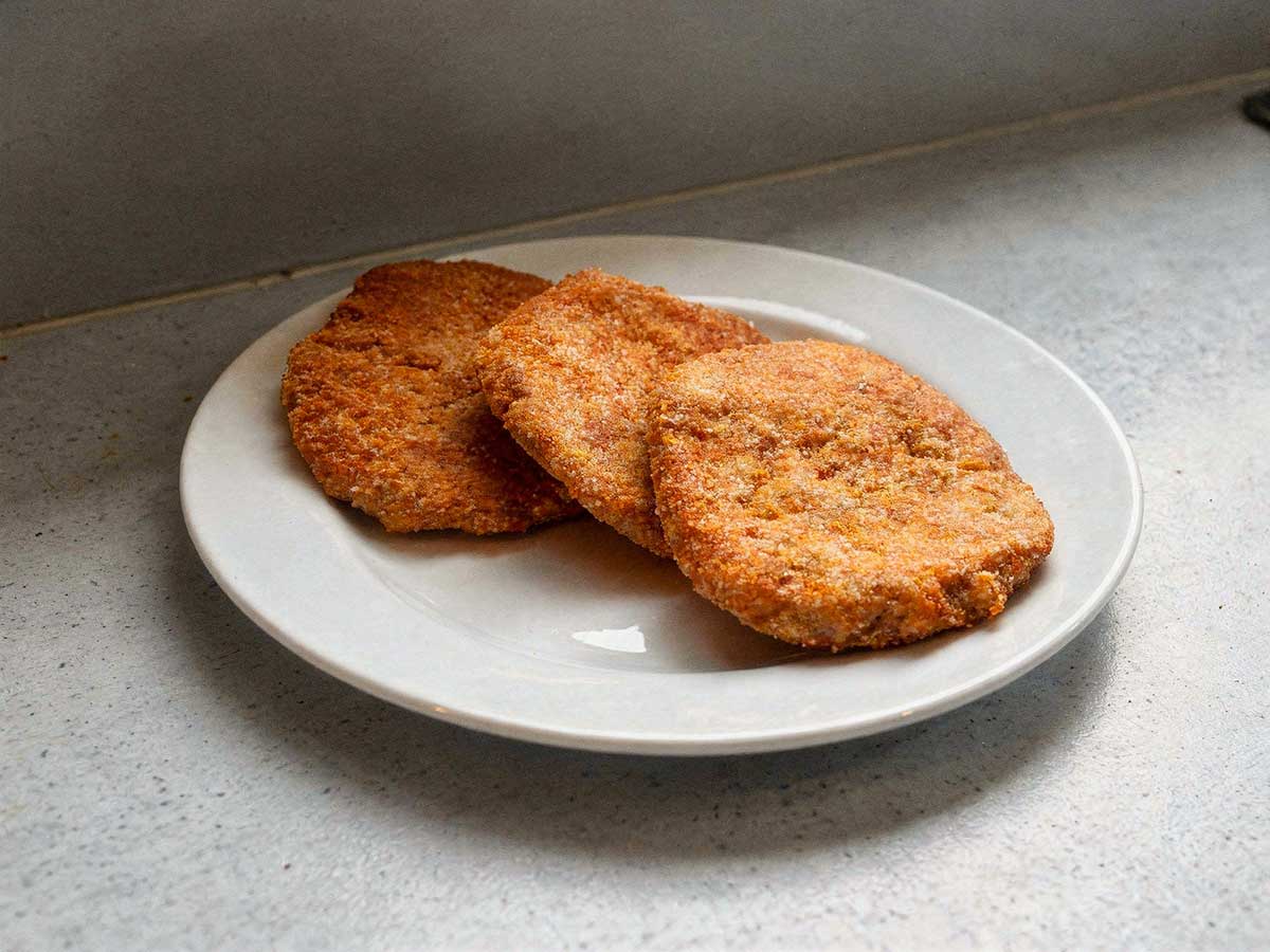 3 gehaktschnitzel op een wit bord.