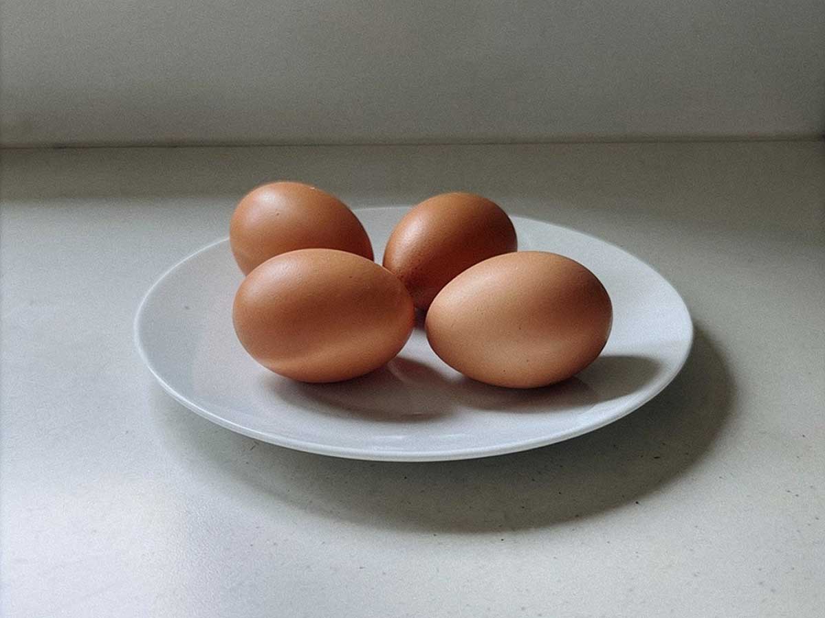 4 gekookte eieren op een bord, voordat ze opgewarmd worden.