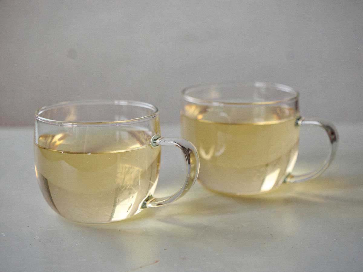2 ronde theeglazen met daarin gemberthee met citroen.