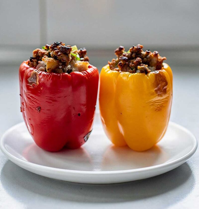 2 gevulde paprika's (rood en geel) staan klaar om op te warmen.