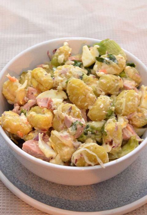 Een salade met gekookte gnocchi, in een wit schaaltje.