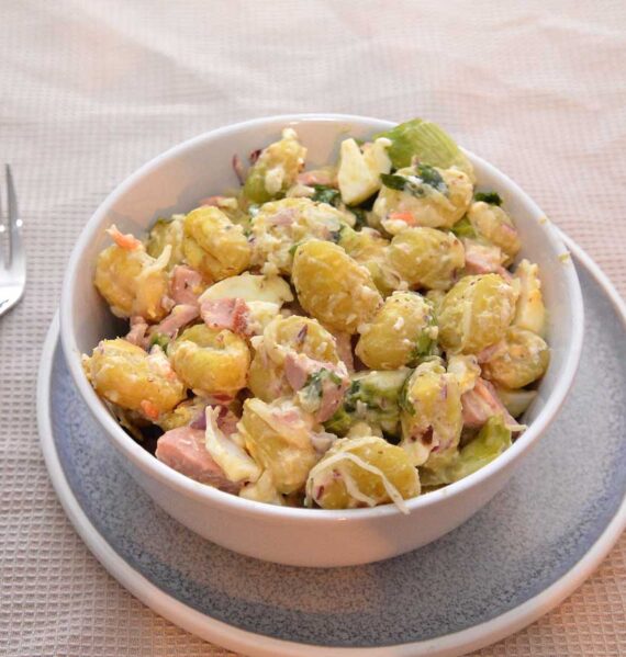 Een salade met gekookte gnocchi, in een wit schaaltje.