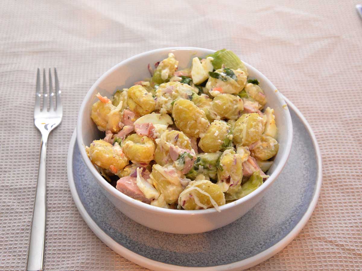 Een salade met gekookte gnocchi, in een wit schaaltje.