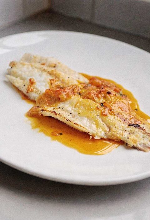 Een gebakken grietfilet op een wit bord.