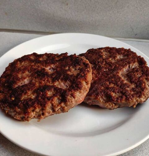 2 hamburger die op een wit bordje opgewarmd zijn.