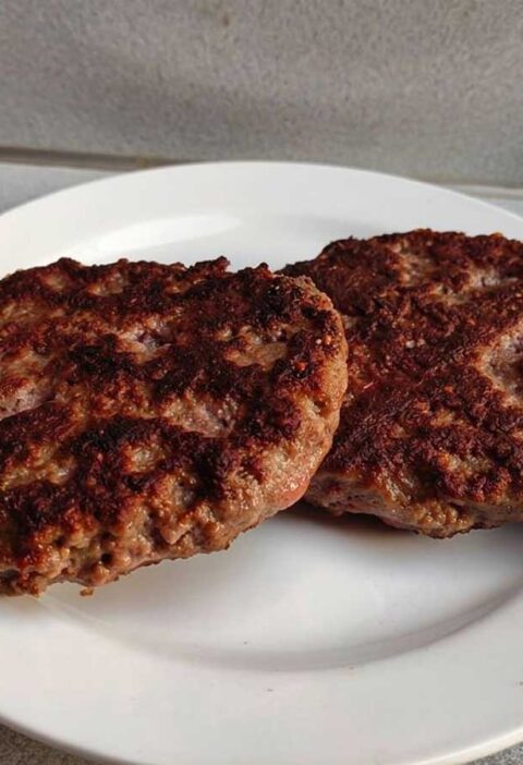 2 hamburger die op een wit bordje opgewarmd zijn.
