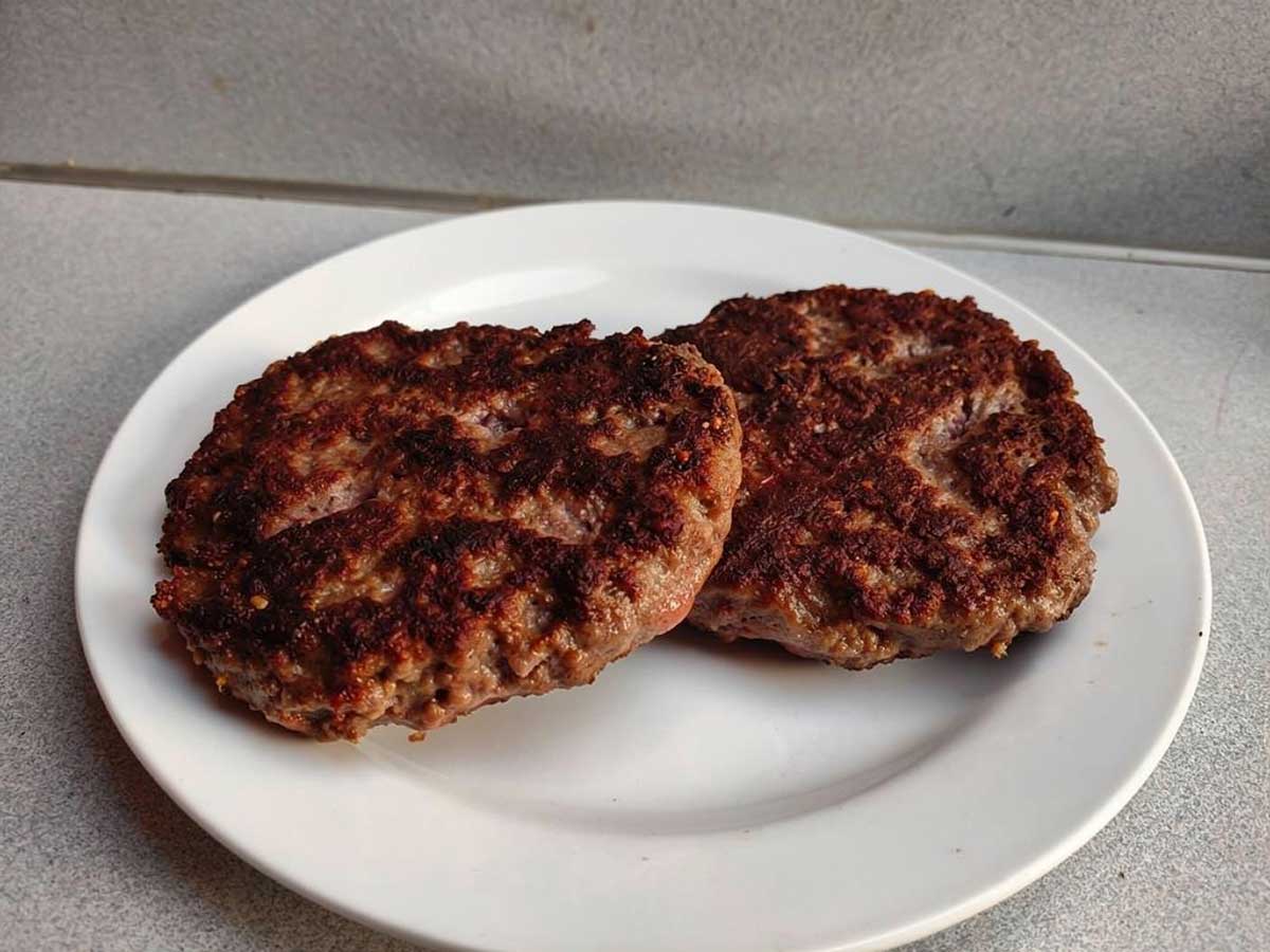 2 hamburger die op een wit bordje opgewarmd zijn.