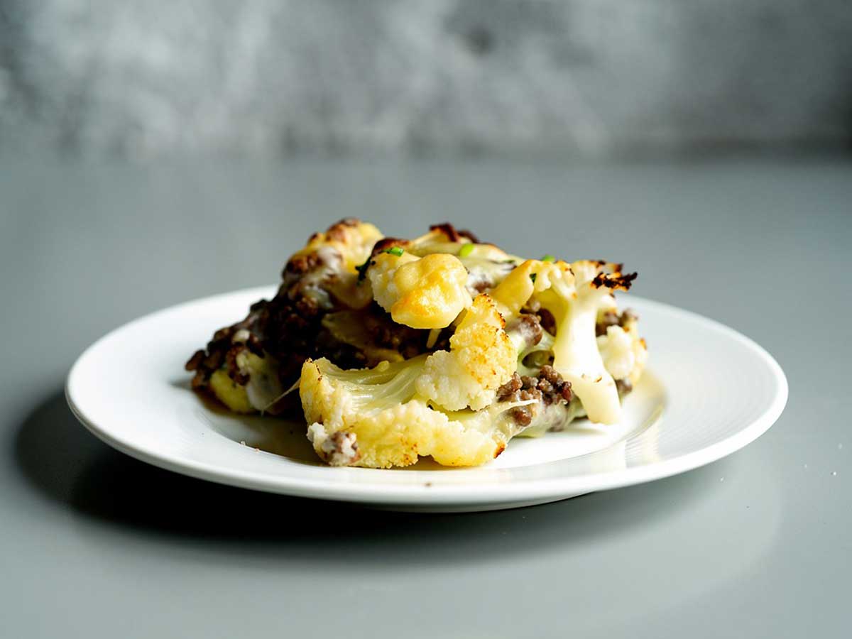 Een portie Hollandse ovenschotel met bloemkool op een wit bord.