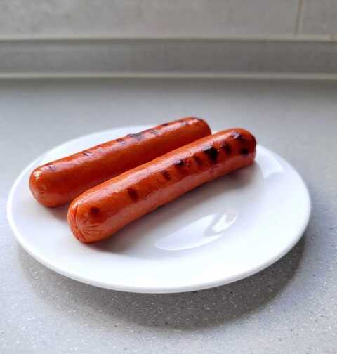 2 opgewarmde hotdogs op een wit bord.