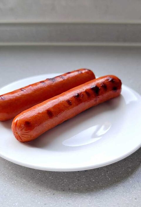 2 opgewarmde hotdogs op een wit bord.
