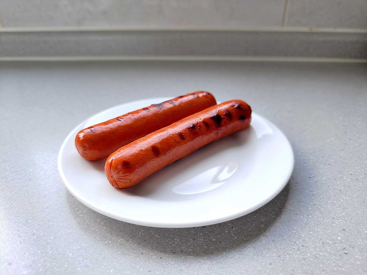 2 opgewarmde hotdogs op een wit bord.
