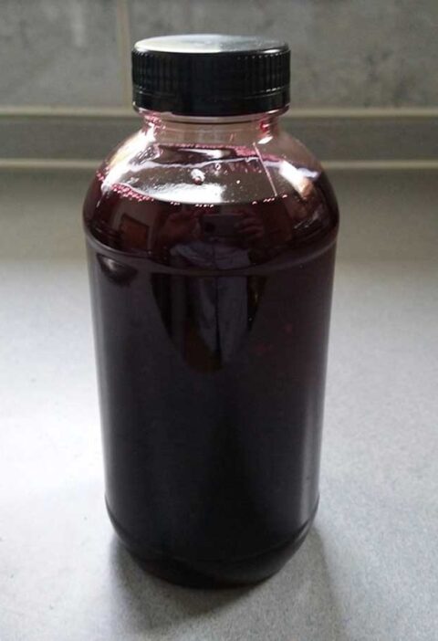 Een fles vol met vlierbessensiroop.