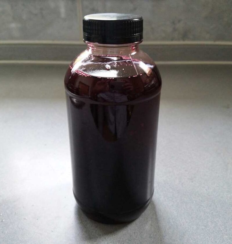 Een fles vol met vlierbessensiroop.